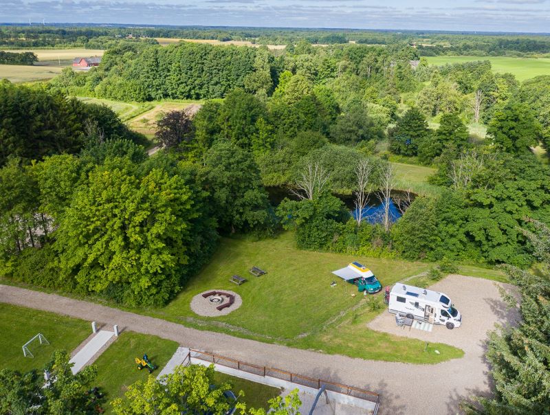 Dronefoto af flot natur og lille autocamperplads ved lille sø