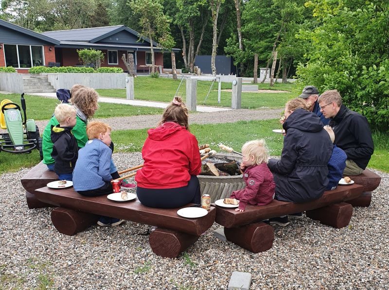 Familien hygger sig ved bålet med bagning af snobrød