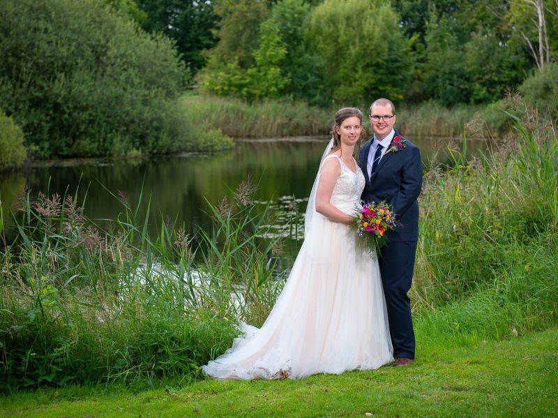 Et smukt brudepar fotograferet ved en lille sø og smuk natur
