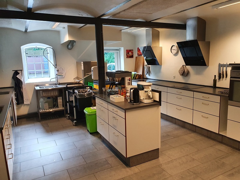 Stort køkken med kaffemaskiner, industriopvaskemaskine, kogeplader, ovne mv. til familiekomsammen